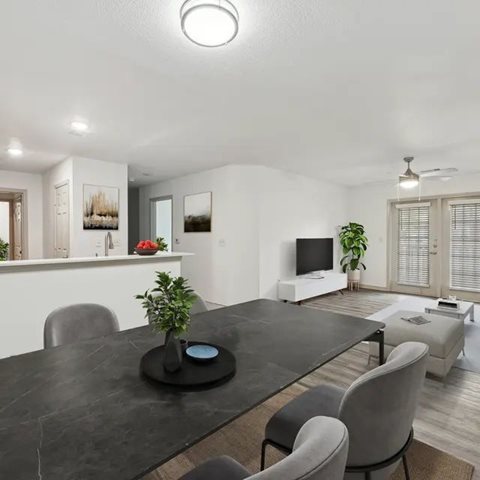 A modern dining room with a black table and grey chairs.